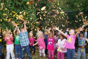 Little Angels children enjoying a flurry of leaves.