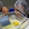 Preschoolers adding eggs for cookie baking