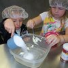 Preschoolers sweetening the cookies with sugar